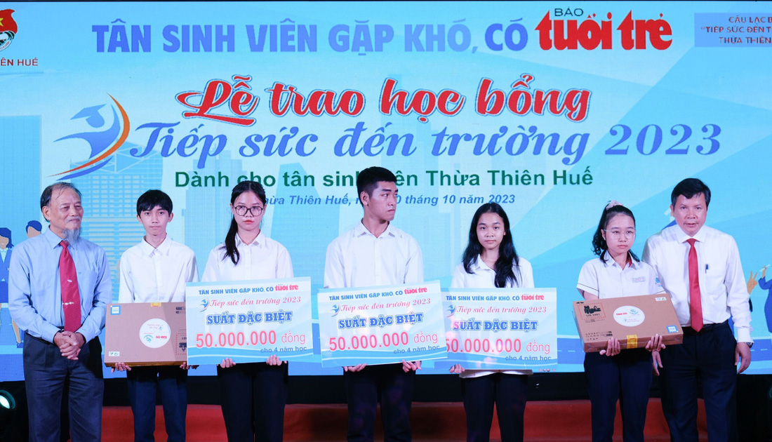 PGS.TS Nguyễn Thiện Tống cùng ông Nguyễn Tân, giám đốc Sở GD-ĐT tỉnh Thừa Thiên - Huế trao phần học bổng đặc biệt và laptop cho các tân sinh viên có hoàn cảnh đặc biệt - Ảnh: TẤN LỰC