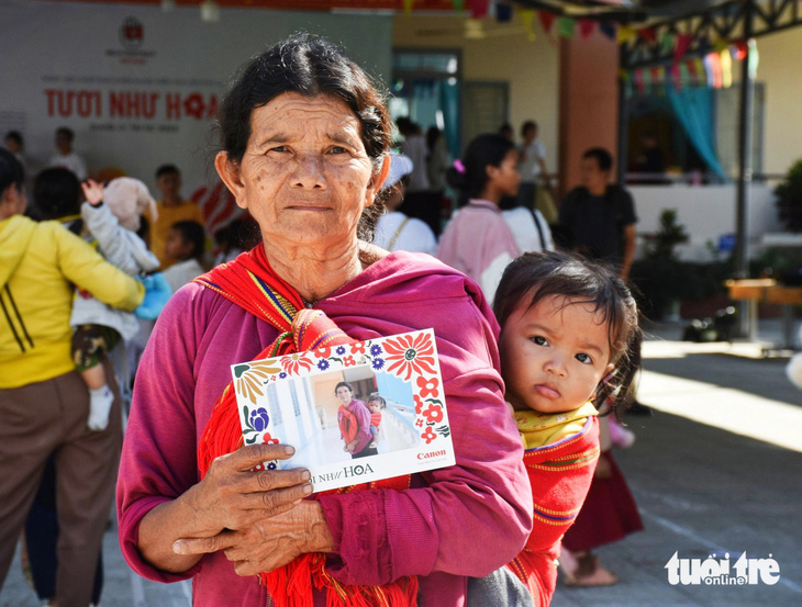 Bà Cà Chơm (xã Giang Ly) địu cháu trên lưng đến điểm chụp ảnh chân dung - Ảnh: TRẦN HOÀI