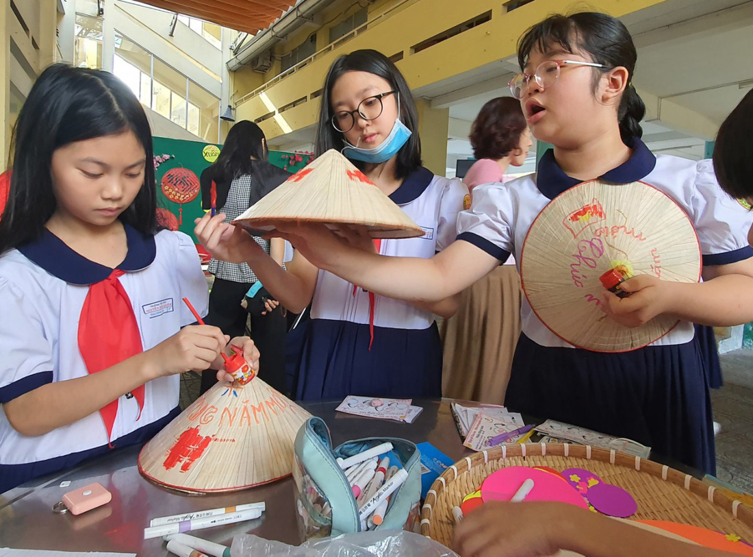 Sau khi vượt qua các trạm thử thách, học sinh dừng chân ở trạm cuối cùng &quot;Xuân với hình tròn&quot; để trang trí nón lá, lắp ráp... - Ảnh: HOÀNG HƯƠNG