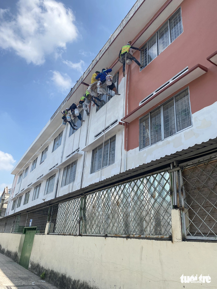 Đội ngũ thi công đang sơn sửa bên ngoài Trường tiểu học Trần Văn Vân - Ảnh: NGỌC PHƯỢNG