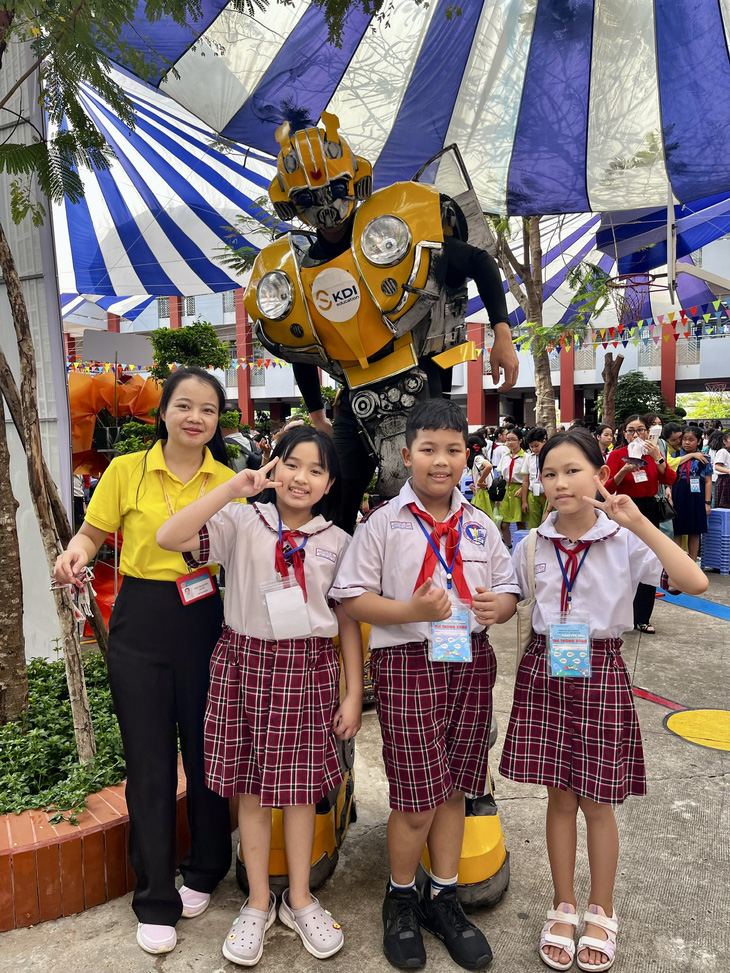 Học sinh tiểu học TP.HCM năm học 2023-2024 vui vẻ tạo dáng bên nhân vật robot tại Ngày hội STEM sáng 5-4 - Ảnh: MỸ DUNG