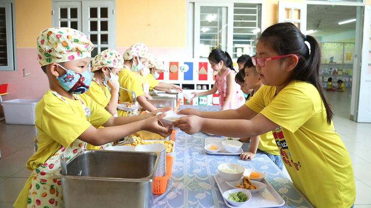 Học sinh lớp lá 4 Trường mầm non Sơn Ca 3, phường Hiệp Bình Chánh, TP Thủ Đức (TP.HCM) mặc tạp dề, múc cơm, canh cho các bạn - Ảnh: PHƯƠNG QUYÊN