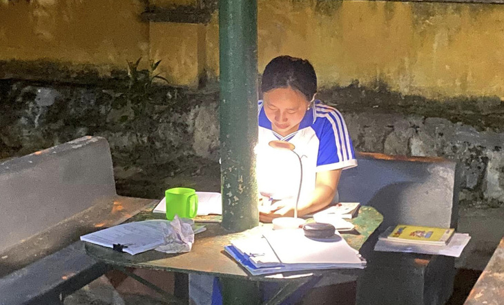 Một nữ sinh Trường phổ thông dân tộc nội trú THCS & THPT Si Ma Cai ngồi ôn bài trong một góc sân trường giữa đêm