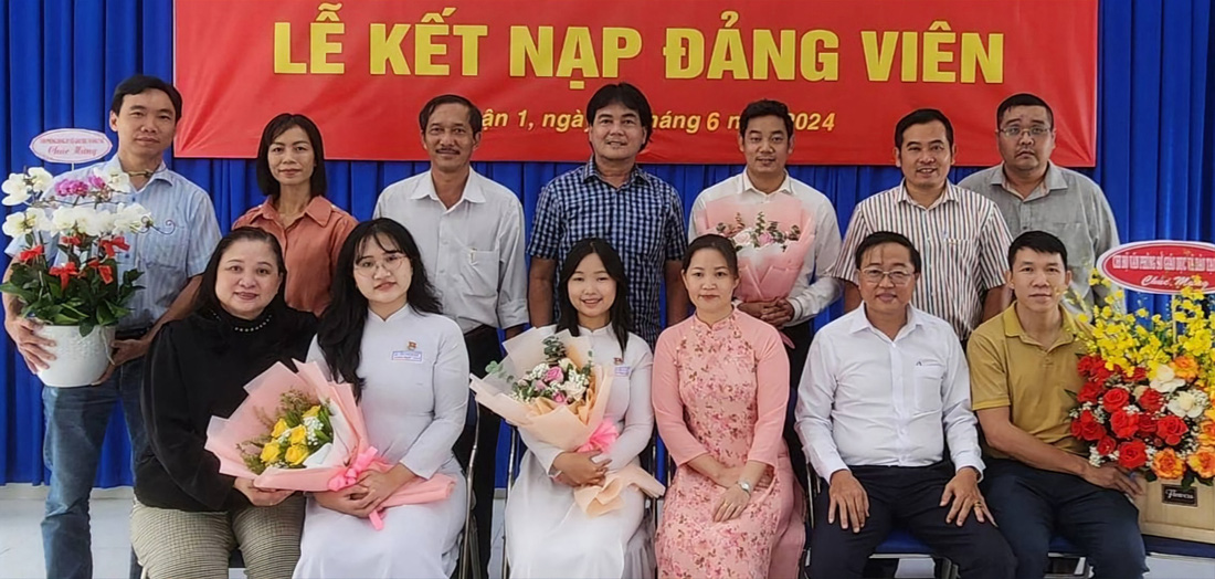Thầy Duy (đứng thứ 3 từ phải sang), học sinh Khánh Ngọc (ngồi thứ 2 từ trái sang), Phương Trang (ngồi thứ 3 từ trái sang) cùng các thầy cô và gia đình tại Lễ kết nạp Đảng - Ảnh: T.P